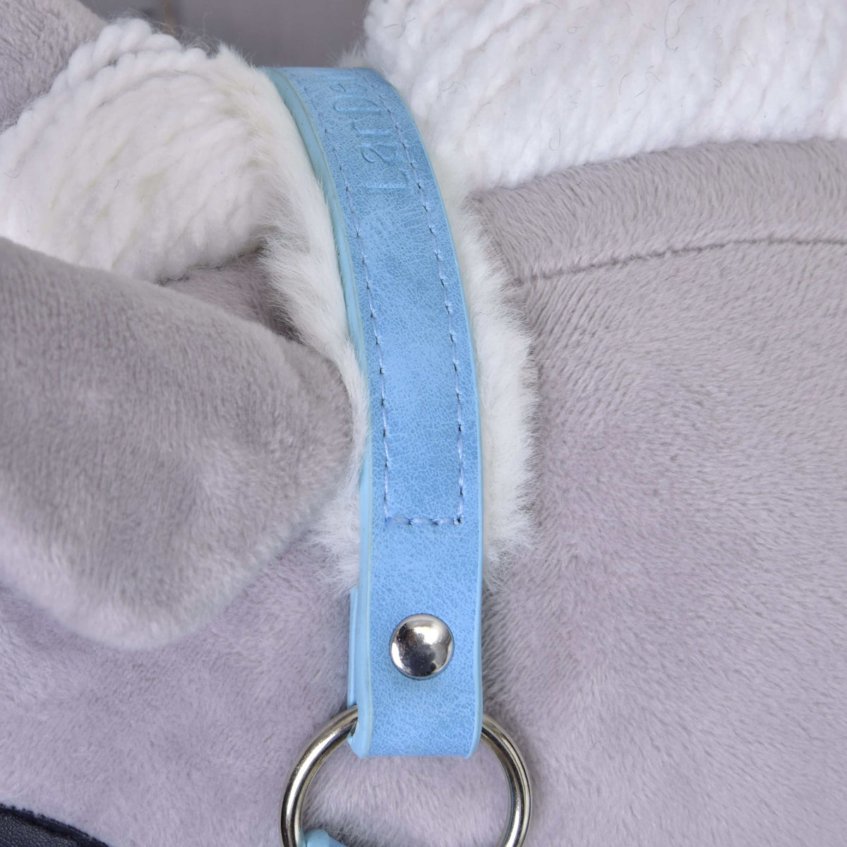 Close-up of the pastel blue leatherette headpiece with stitched edges, embossed lettering and white fur lining