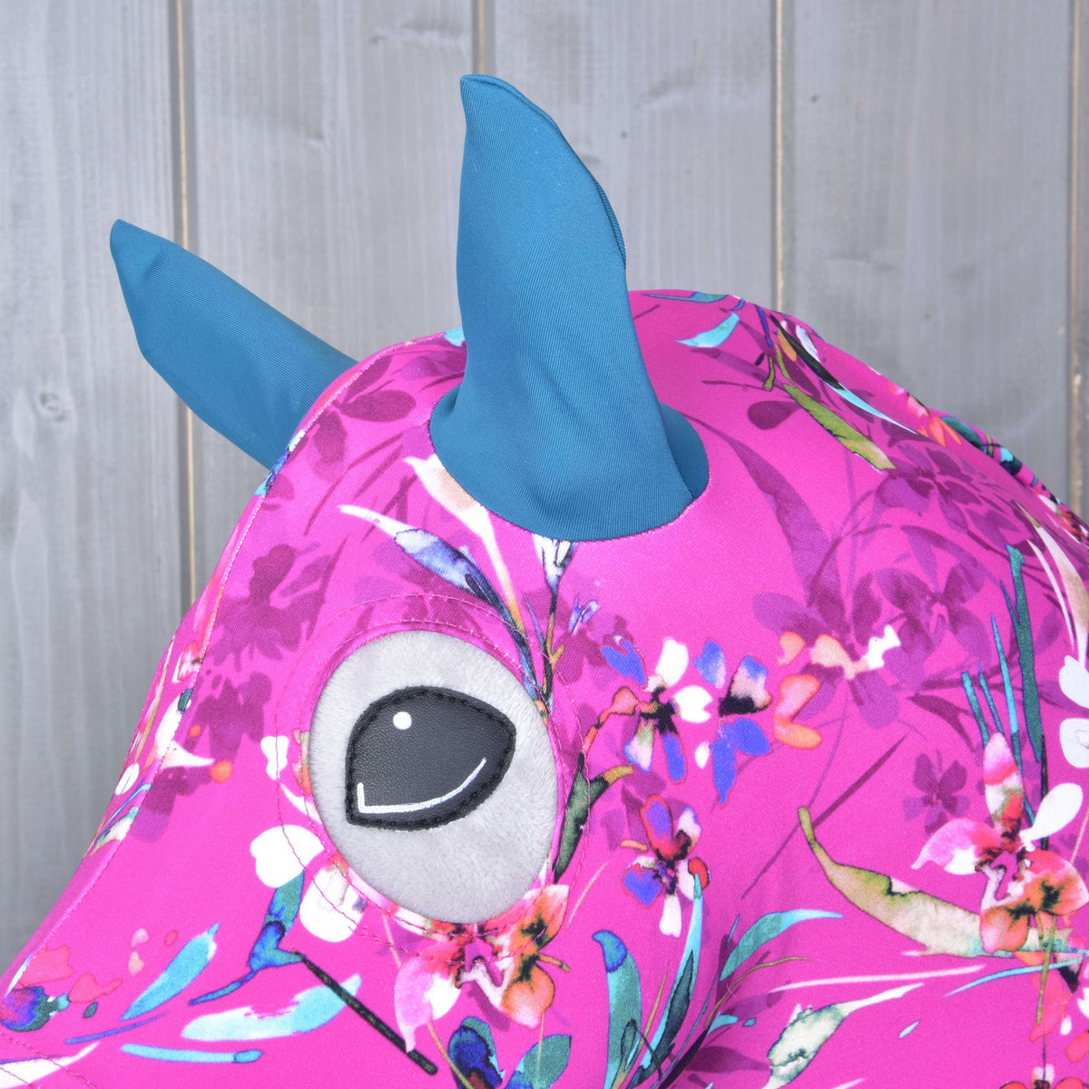 Close-up of the teal ears and eye opening on the magenta Lycra with white and coral flowers on a grey Hobby Horse