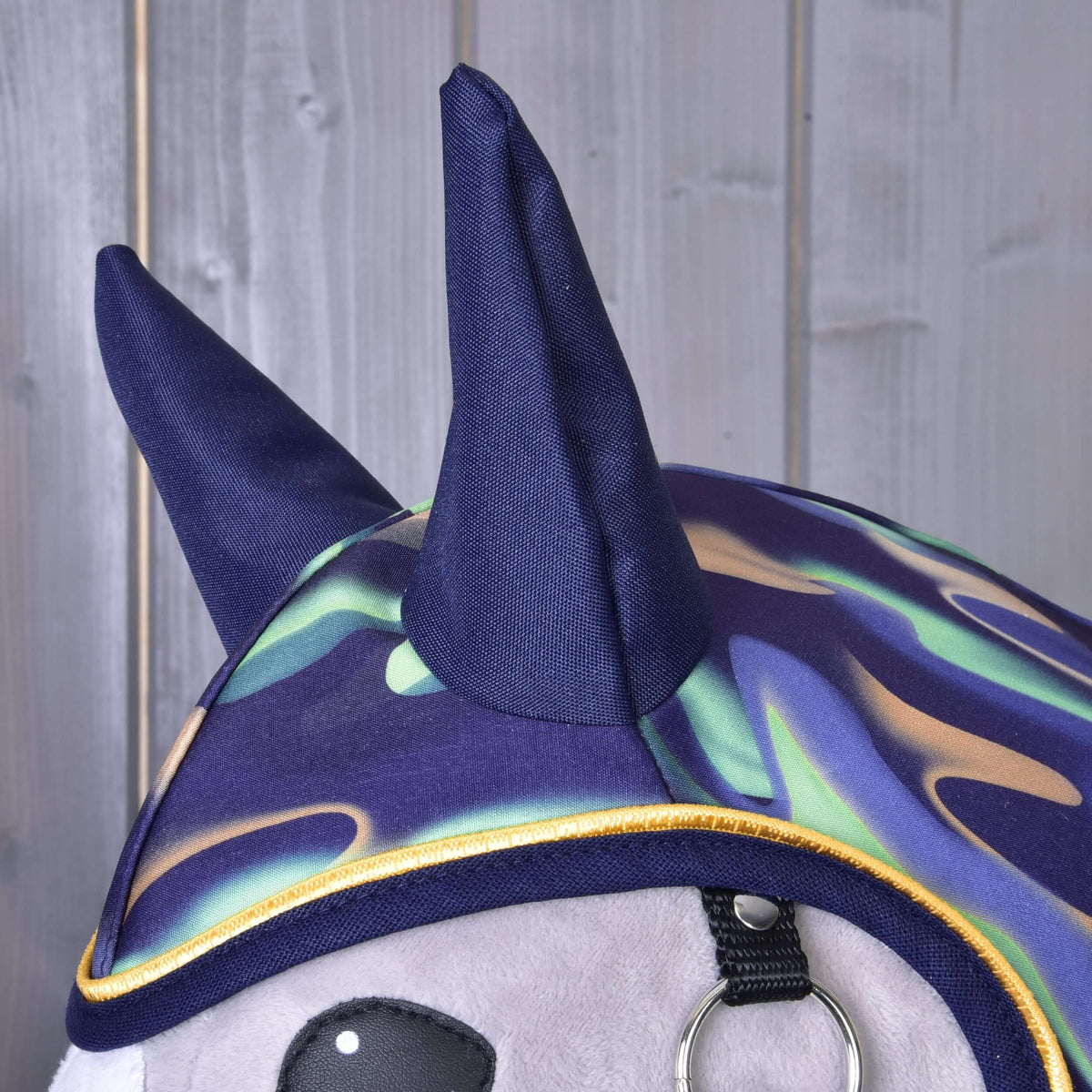 Närbild av de marinblå öronskydden och det vågiga mönstret i mint, lila och beige med gul passpoal på Hobby Horse regntäcke Rainbow