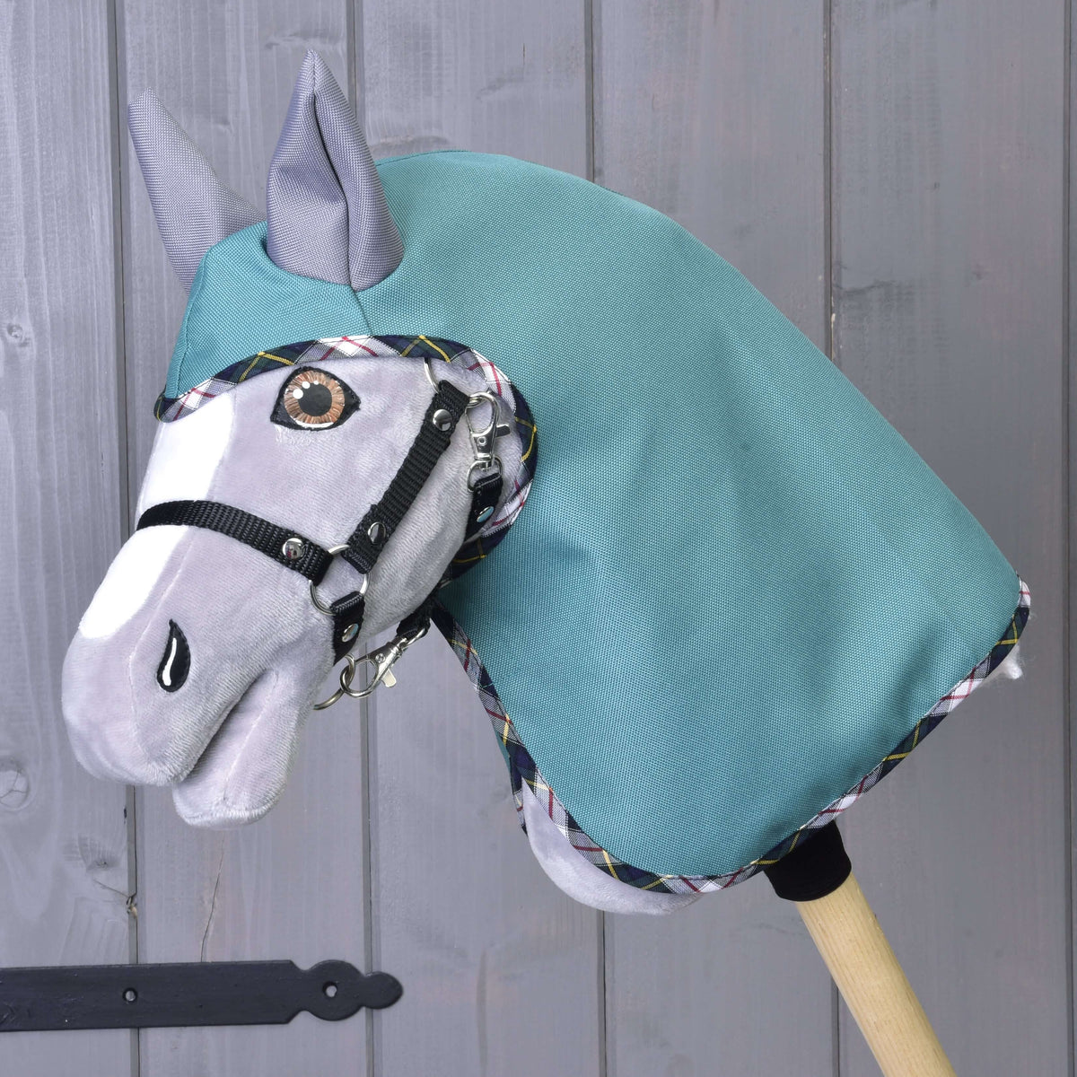 Grey Hobby Horse wearing the sea-green Summer raincoat Emerald with grey ears and a black halter, front view