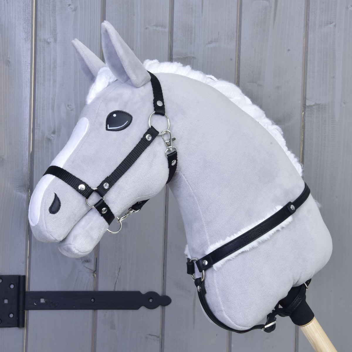 Light grey Hobby Horse in a black halter wearing the black breastgirth with white fur at the base of the neck