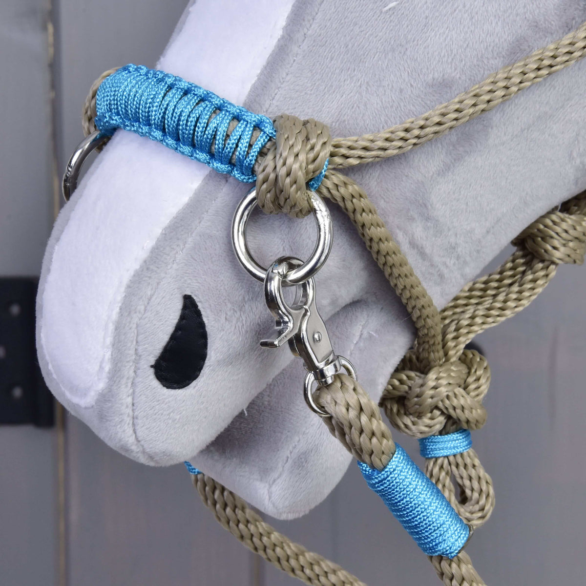 Närbild på nosremmen på Hobby Horse repset Nature Blue: blå flätad lindning, beige repknutar, silverfärgad ring och karbinhake