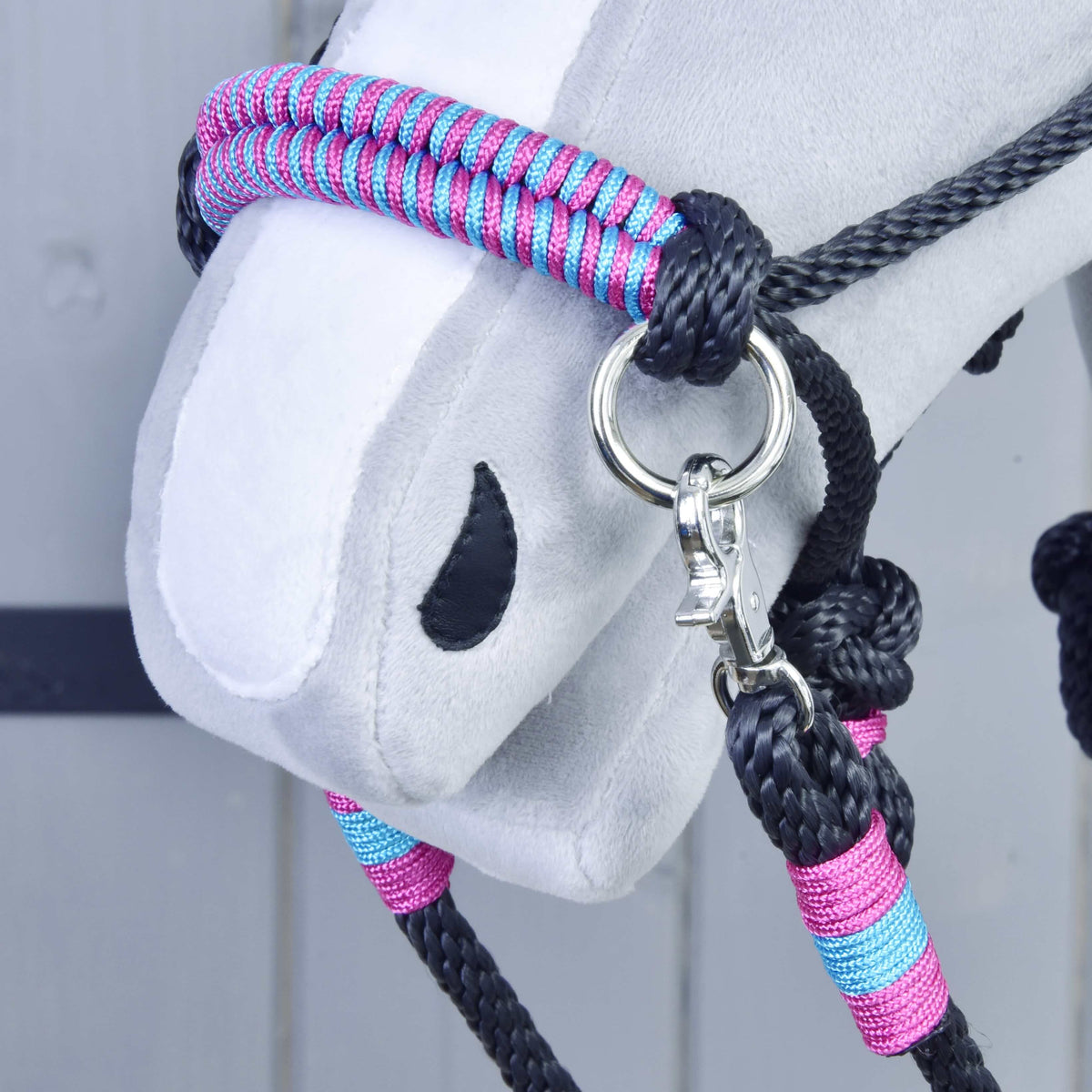 Närbild på nosremmen på Hobby Horse repset Princess, flätad i rosa och turkos, med silverfärgad ring och karbinhake