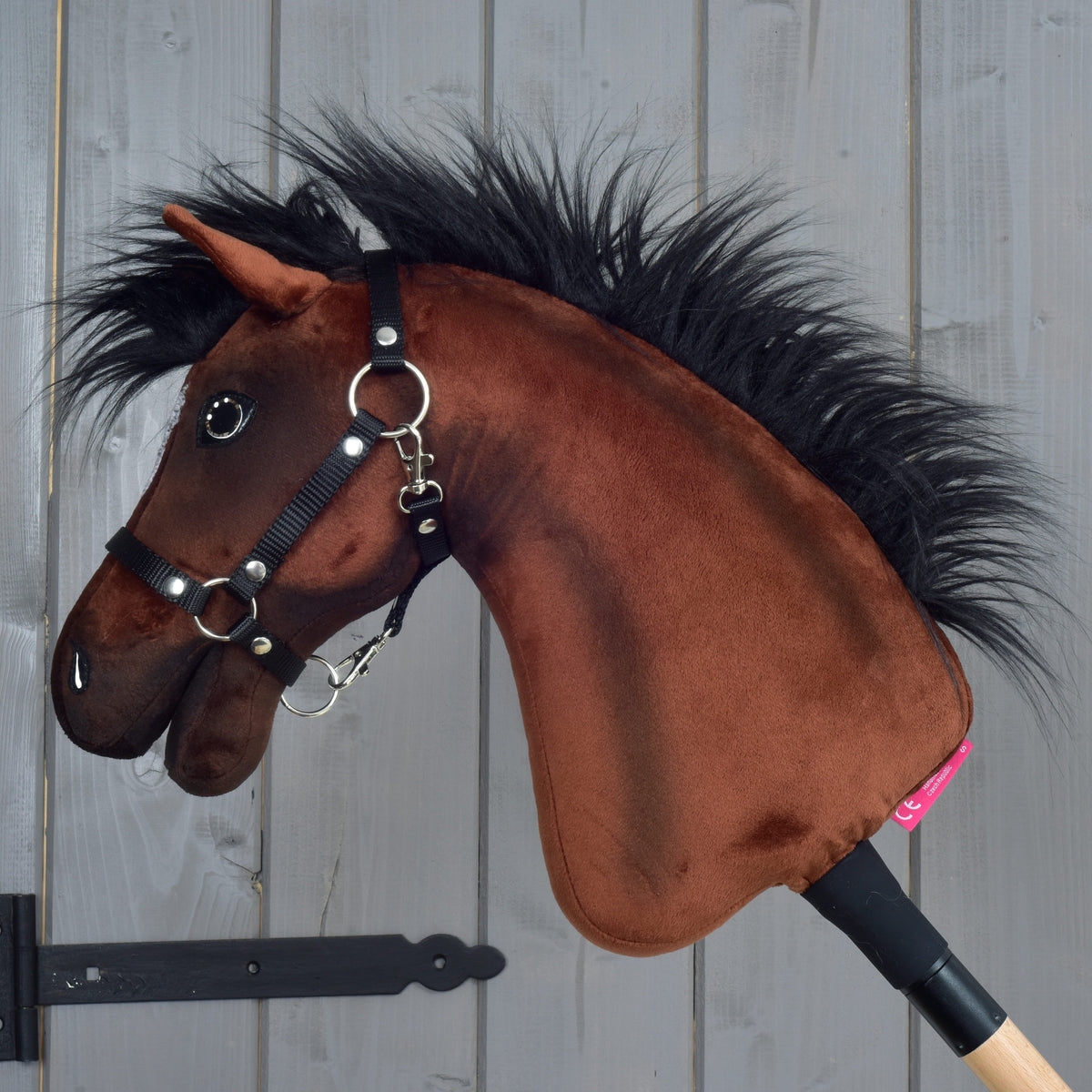 Hobby Horse Roger i vänsterprofil, brun plysch med lång svart man, svart grimma av vävt band och en ljus träkäpp