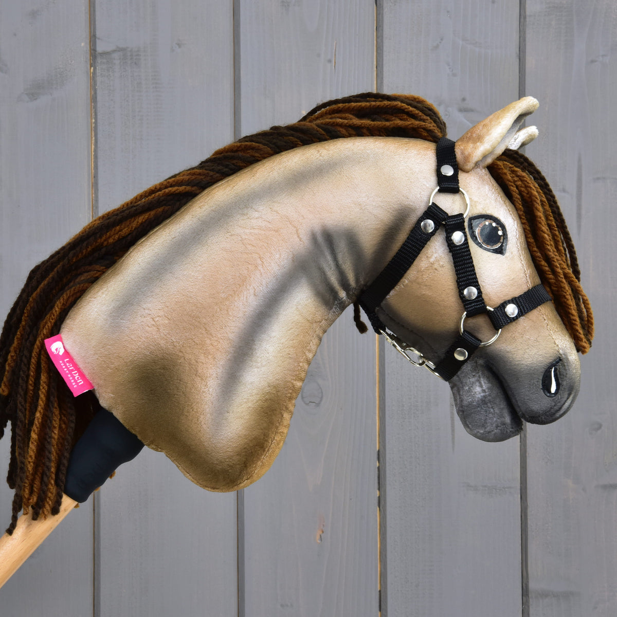 Hobby Horse Ruby i höger profil med rosa etikett från LarDen på halsen, svart grimma och brun man av garn