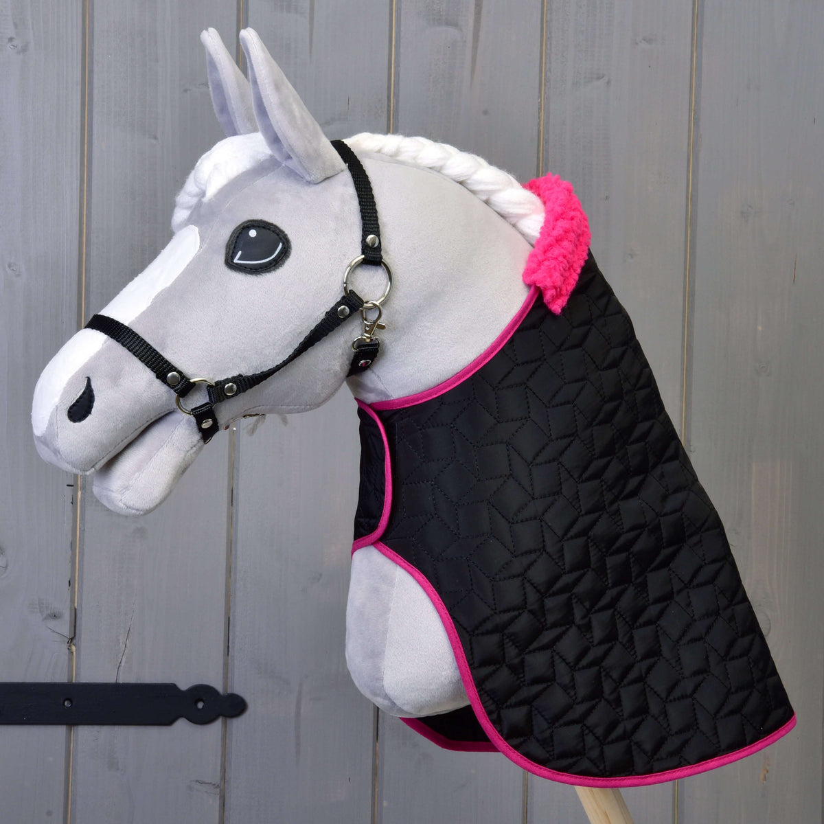Grey Hobby Horse in a black halter wearing only the quilted black blanket with pink binding and pink fur collar