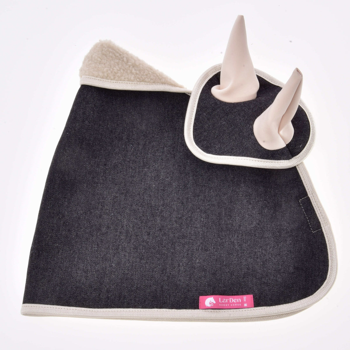 Mörkt jeanstäcke med flughuvan ovanpå, fluffig beige sherpakrage, krämvitt kantband och rosa etikett från LarDen