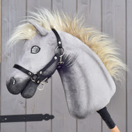 LarDen Hobby Horse Silver Dream med grått plyschhuvud, krämvit man och svart grimma, från sidan vid en stalldörr i trä