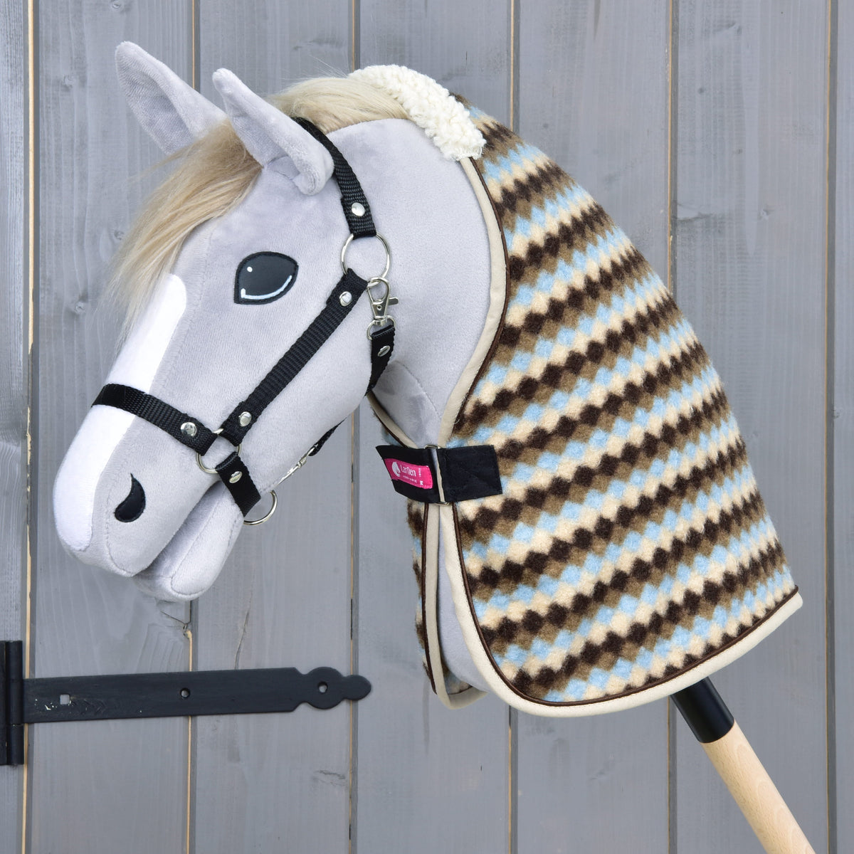 Grå käpphäst med blond man och svart grimma som bär stalltäcket Pastel Argyle med beige kantband
