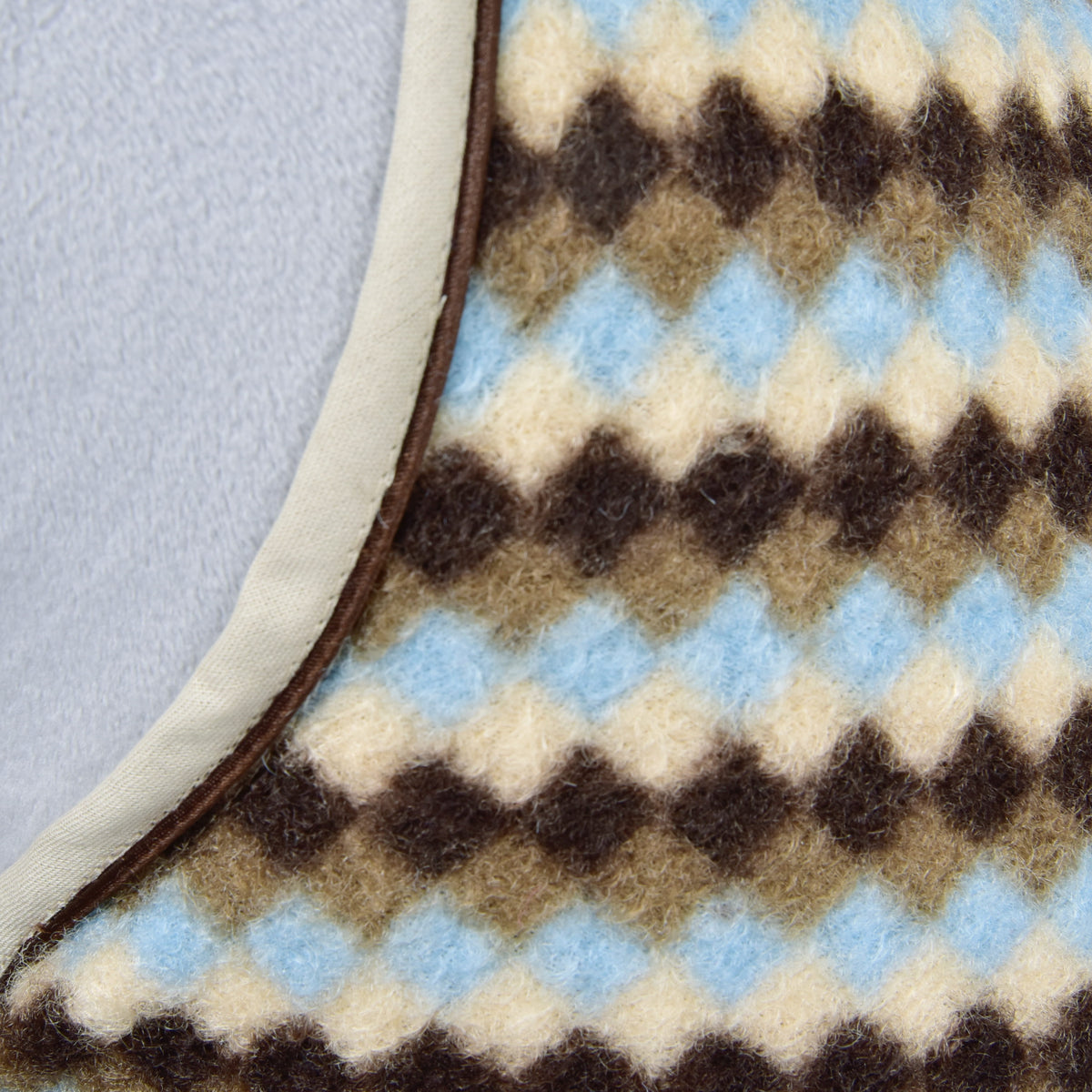 Makrobild av fleecen med romber i brunt, gråbrunt, krämvitt och ljusblått och det beige kantbandet på Hobby Horse stalltäcke Pastel Argyle