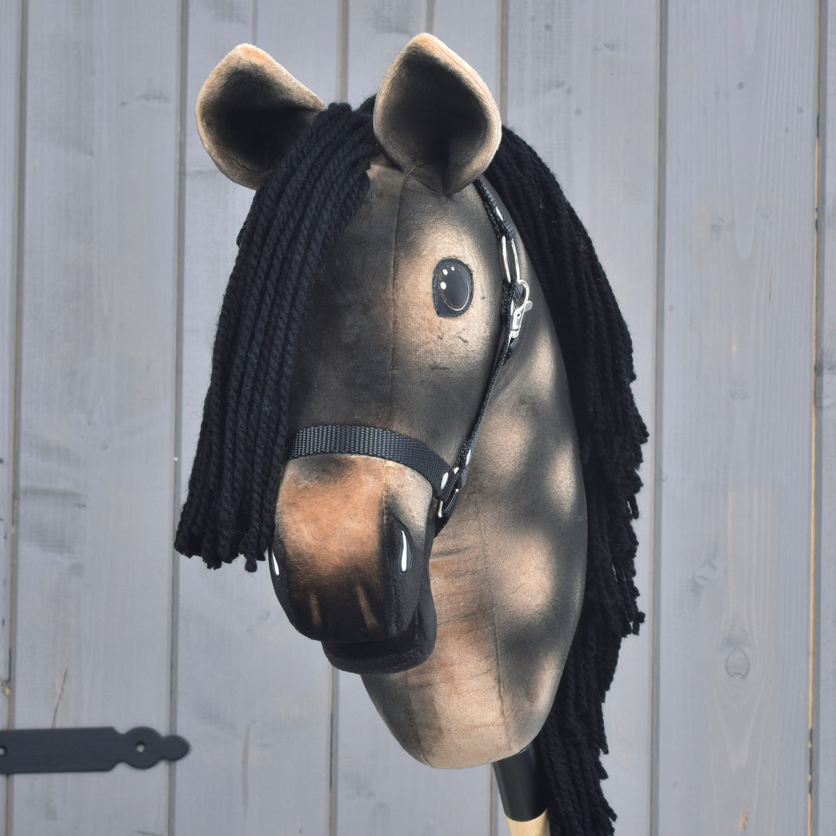 Hobby Horse Stormy med svart grimma framifrån, svart pannlugg av garn, ljusbrun mule och bruna öron med ljus kant