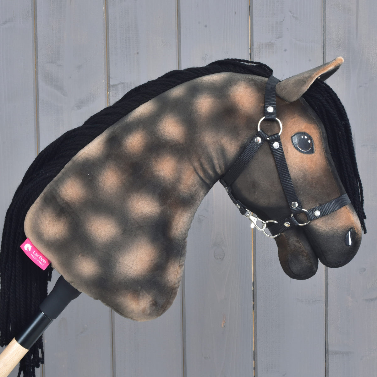 Hobby Horse Stormy med svart grimma vänd åt höger, ljusa apeltecken på den bruna halsen och den rosa LarDen-etiketten