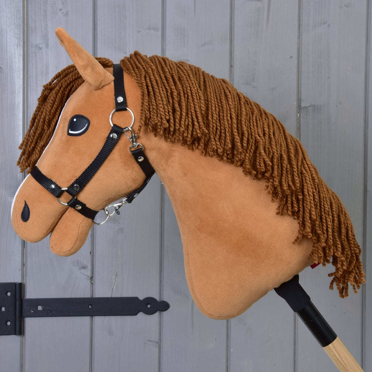 Hobby Horse Wendy i profil med sin långa bruna man av garn, svart grimma och fuxfärgad plysch
