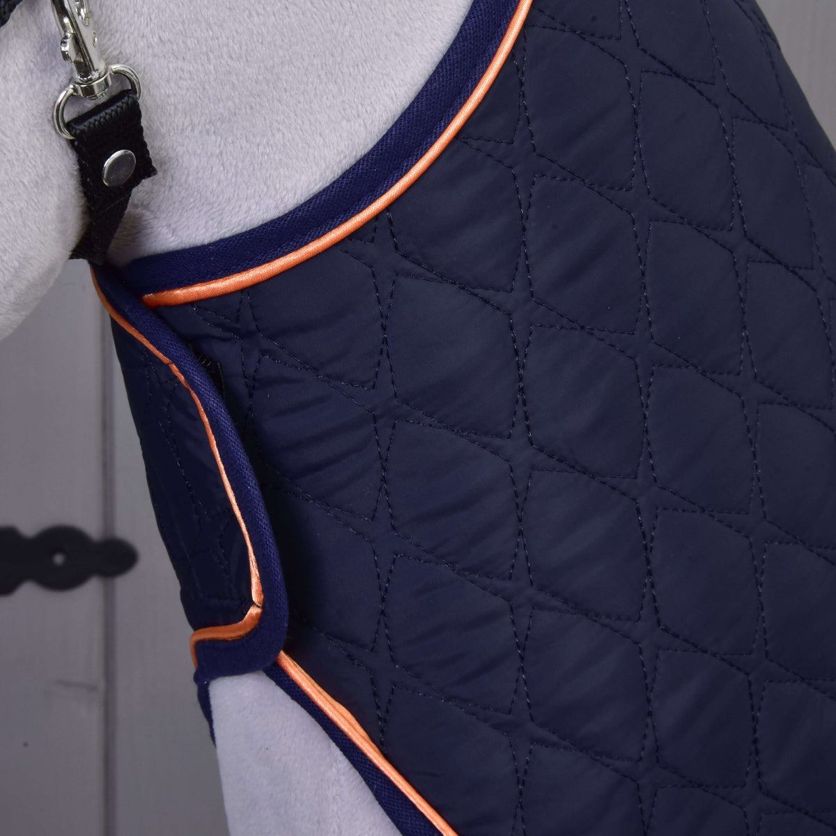 Close-up of the diamond-quilted navy blanket with orange piping around the neck of a grey Hobby Horse
