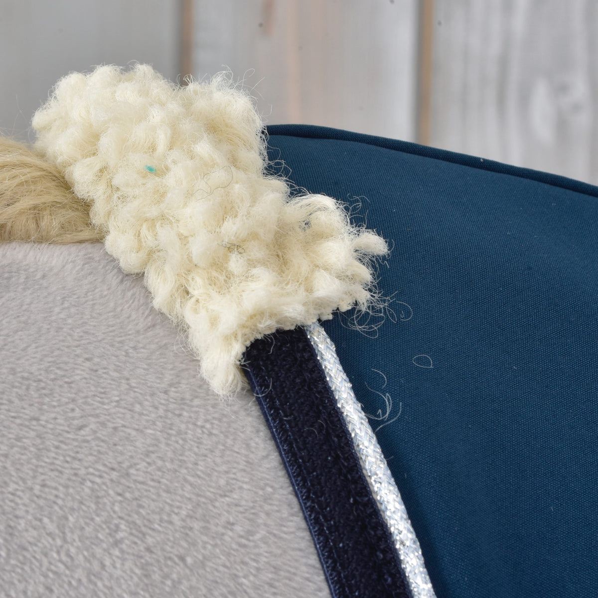 Close-up of the cream curly fleece collar, navy binding and silver glitter piping of the Stable Blanket Winter Sky on a Hobby Horse