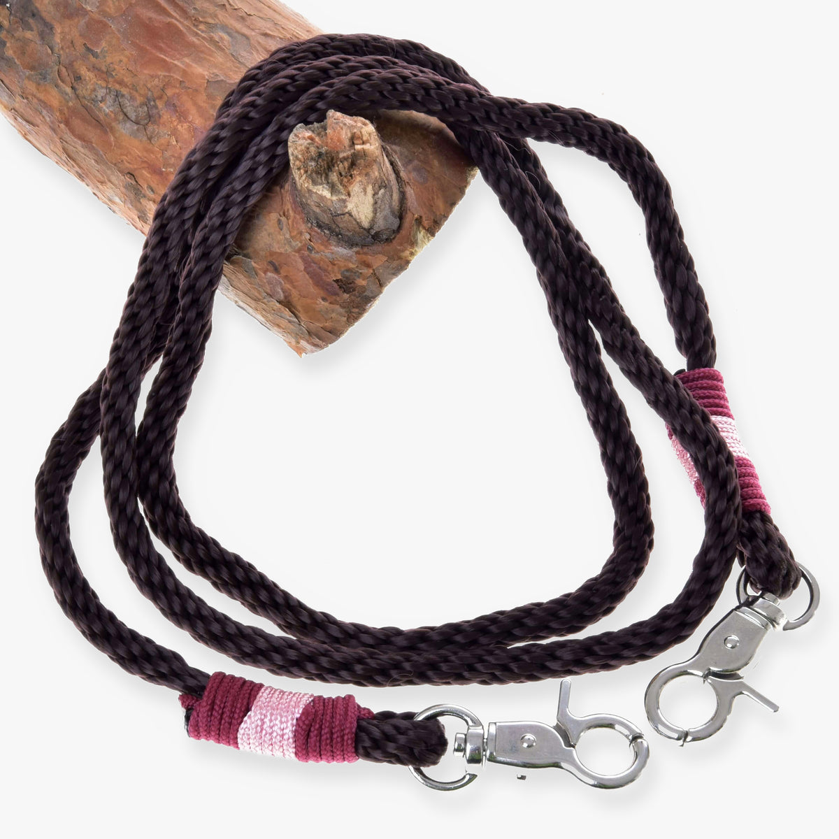 Hobby Horse Reins York by LarDen, dark brown rope reins with pink and burgundy wrapped ends and snap hooks, on a branch
