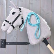 Light grey Hobby Horse in a black halter with the turquoise rope stripe Atlantis lead rope draped over its neck