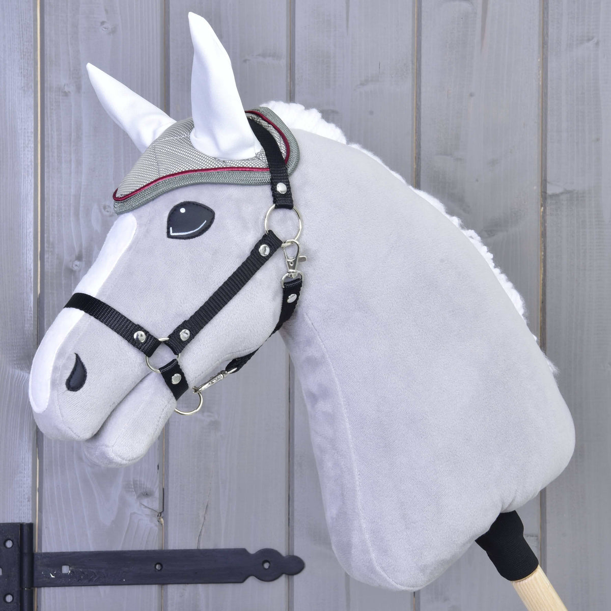 Light grey Hobby Horse in a black halter wearing the silver grey ear bonnet with white ears
