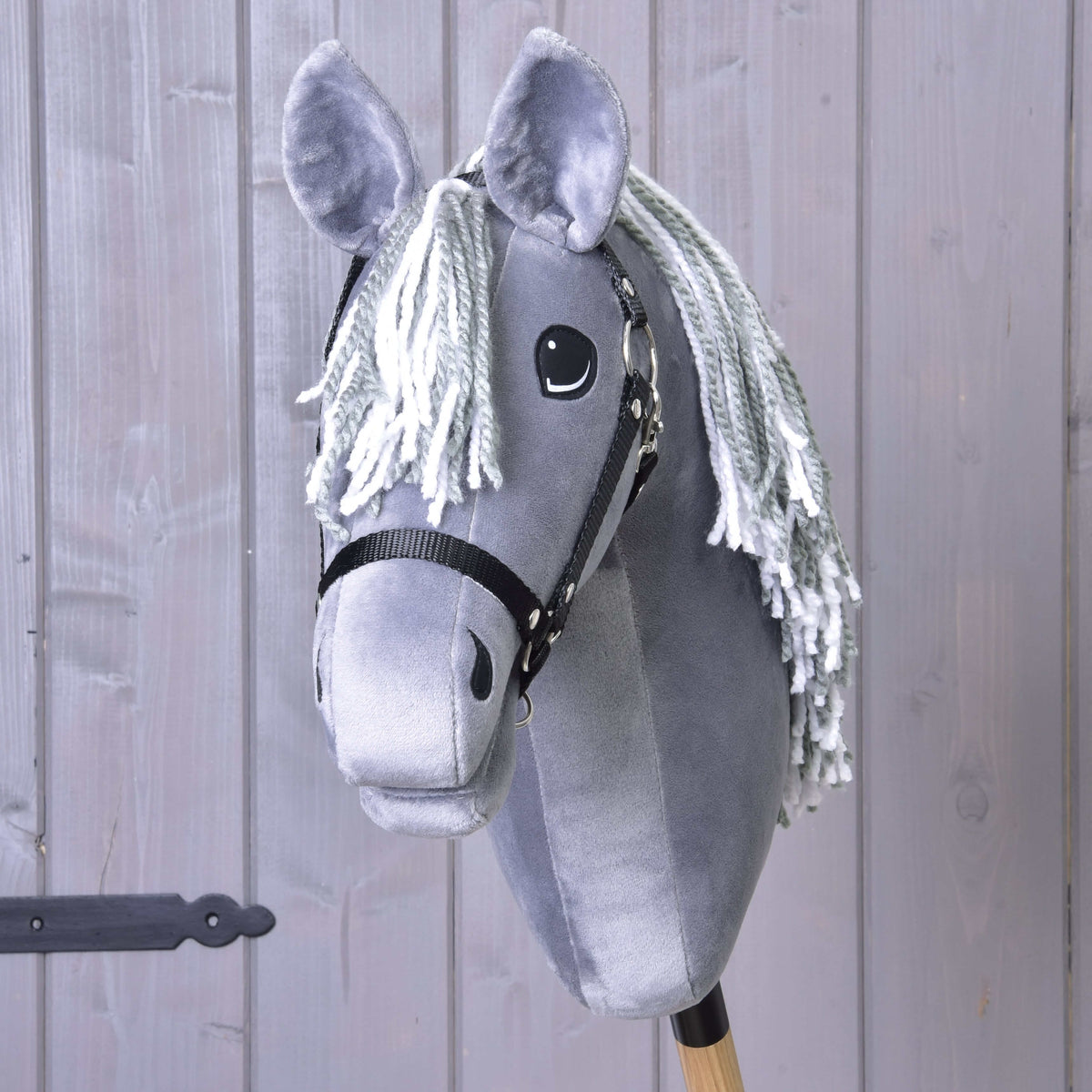 Front view of Hobby Horse Calypso with a grey and white yarn forelock, plain grey face and black halter