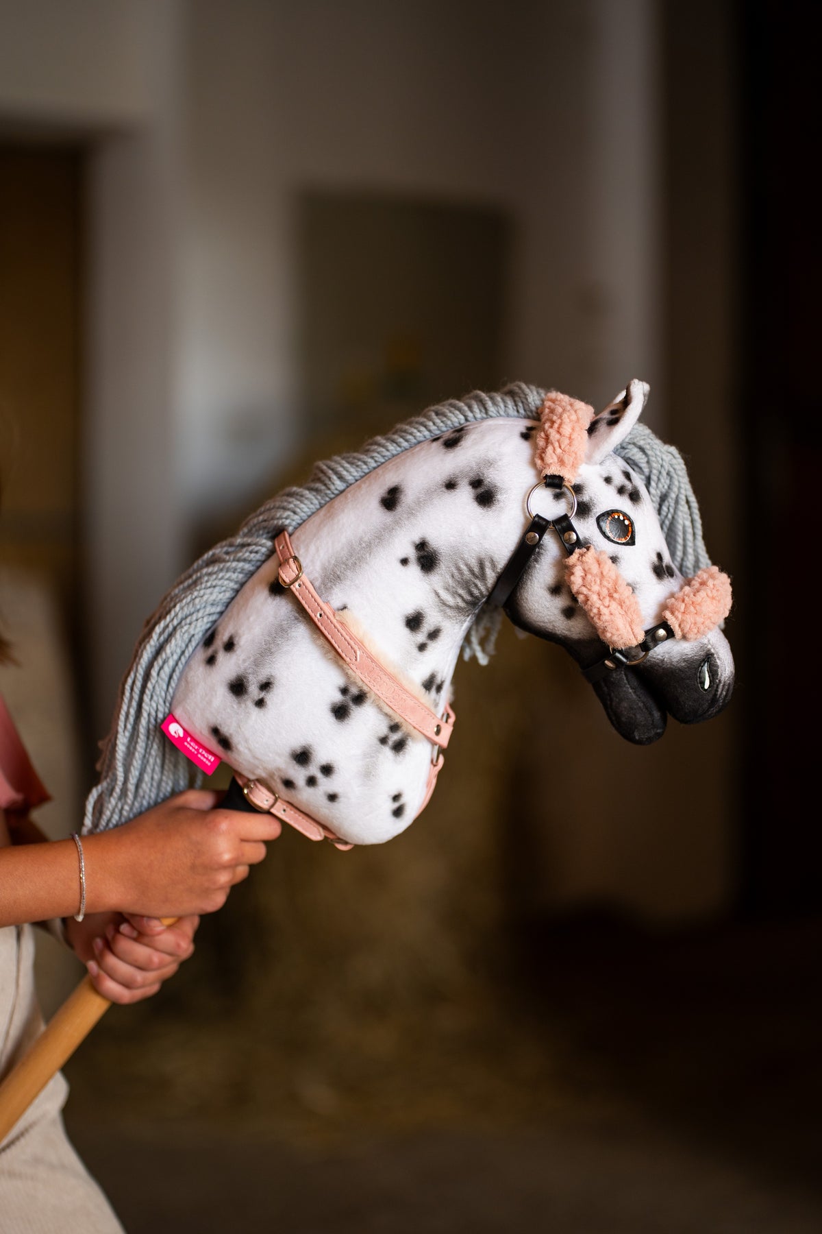 Hobby Horse Chantal up close in a halter with peach pink fur and a dusty pink breastgirth, black spots on the white neck
