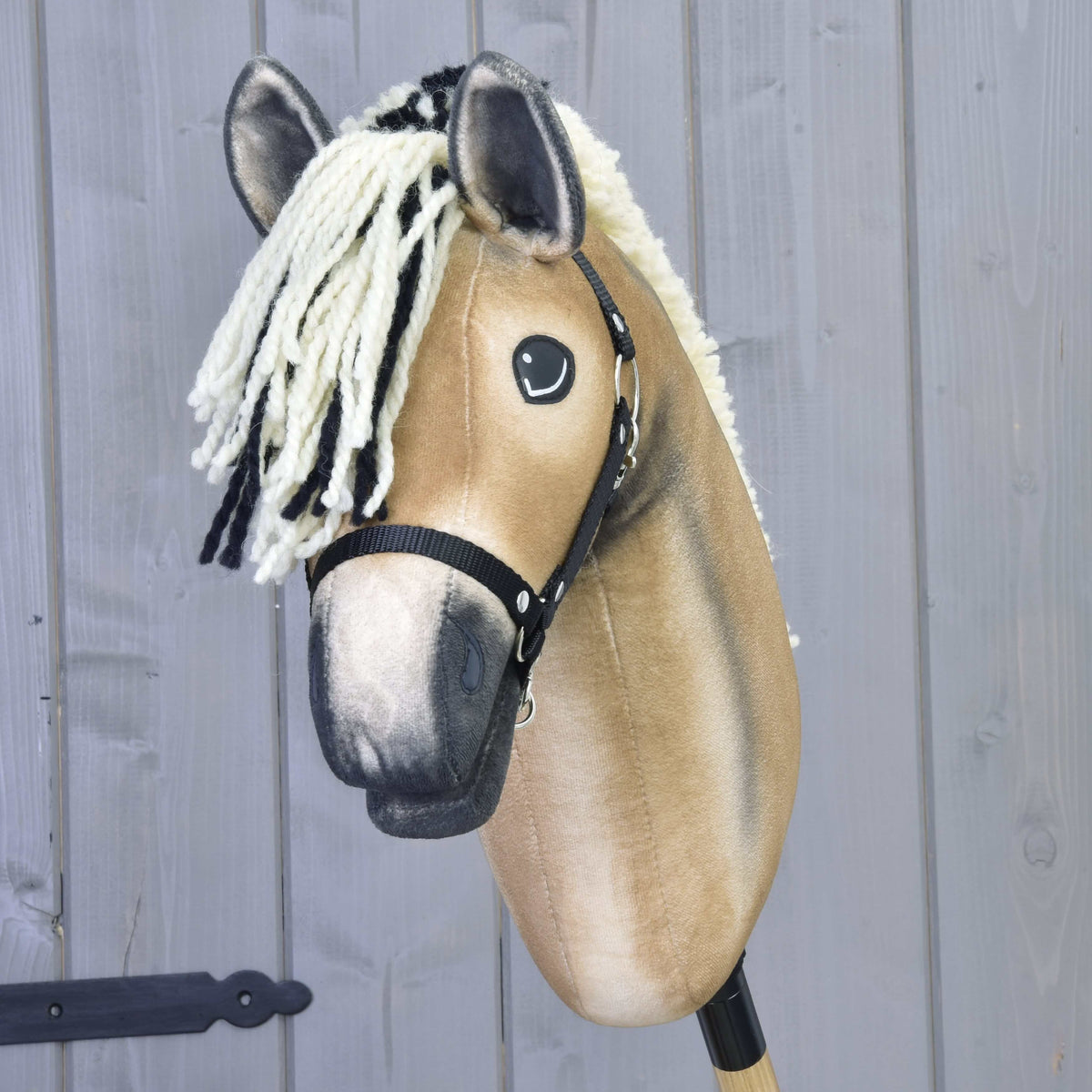 Hobby Horse Colby framifrån med pannlugg av krämfärgat och svart garn, mörka öronspetsar och svart grimma