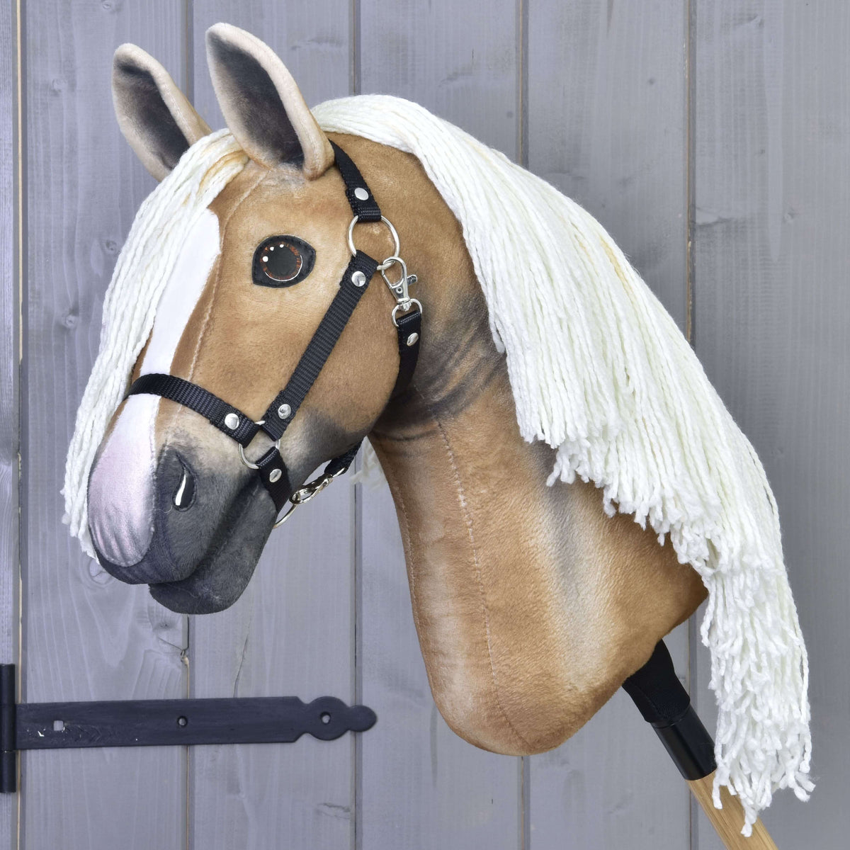 Hobby Horse Connie med svart grimma från LarDen, ett gyllene ljusbrunt käpphästhuvud i plysch med lång krämfärgad man av garn och vit bläs