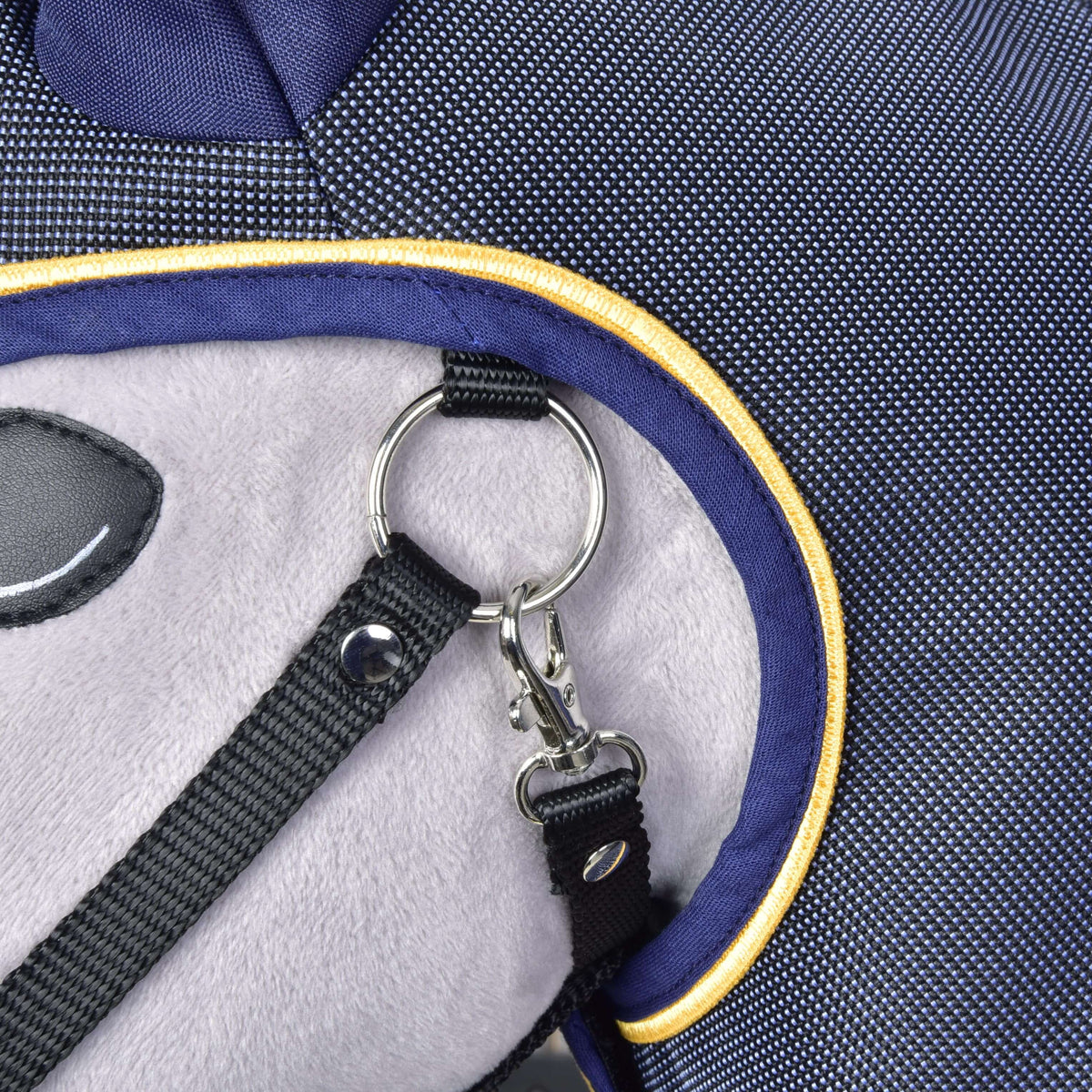 Close-up of the navy binding with gold piping around the face opening of the raincoat, next to the silver halter ring