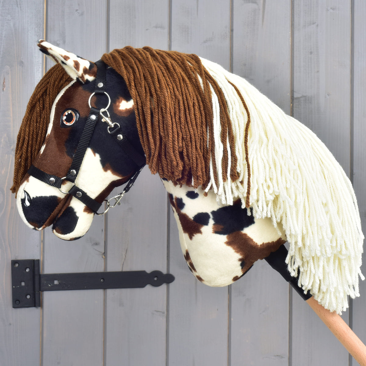 Hobby Horse Dakota med svart grimma vänd åt vänster, tvåfärgad man av brunt och krämvitt garn draperad över halsen
