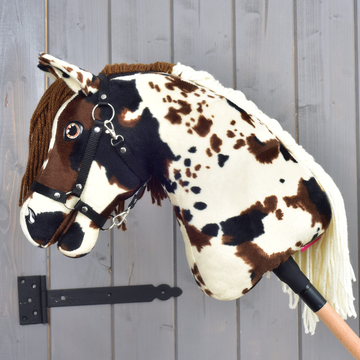 Hobby Horse Dakota med svart grimma i vänsterprofil, fläckig krämvit hals och den krämvita manen av garn längs ryggen
