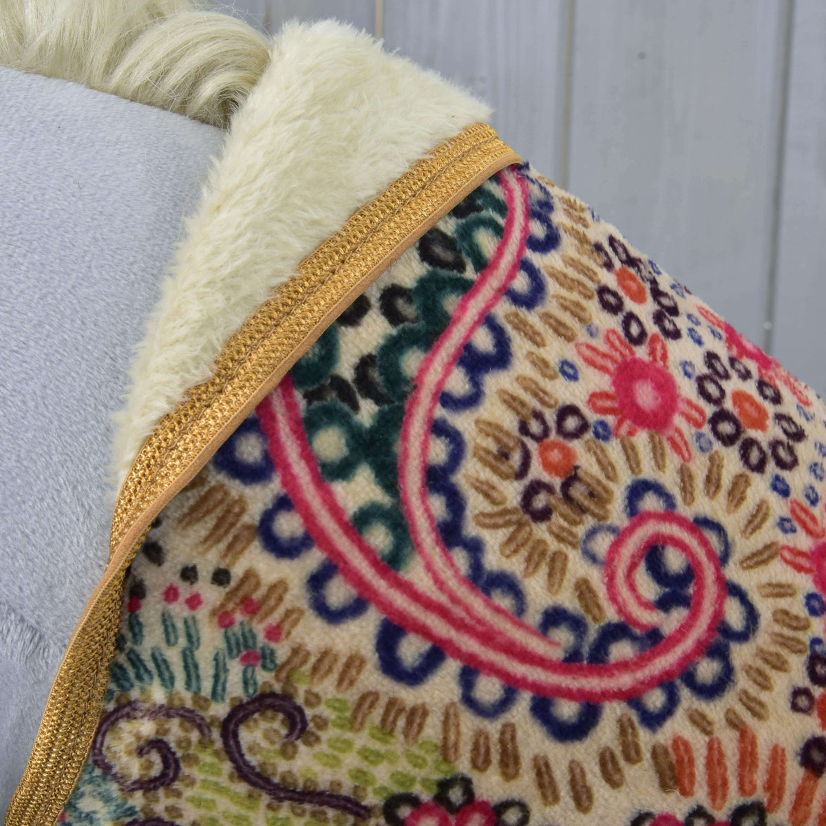 Close-up of the pink, navy and green swirl pattern, cream plush lining and golden brown binding at the neckline