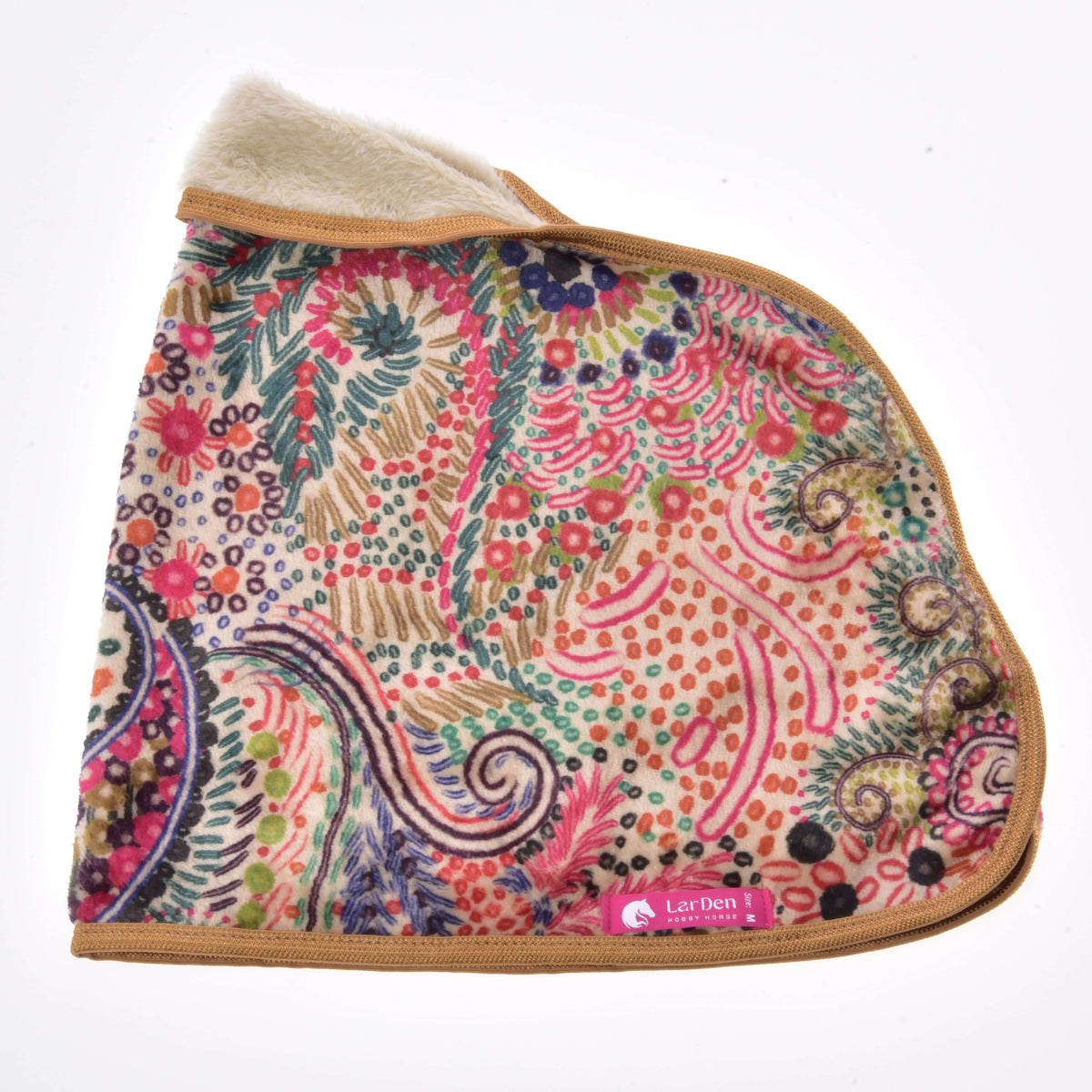 The patterned blanket laid flat from the side with cream lining at the neck, golden brown binding and a pink LarDen label