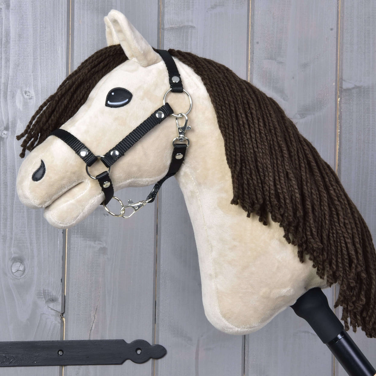 Hobby Horse Frederik LD with black halter from the side, dark brown yarn mane falling over the cream neck, black stick
