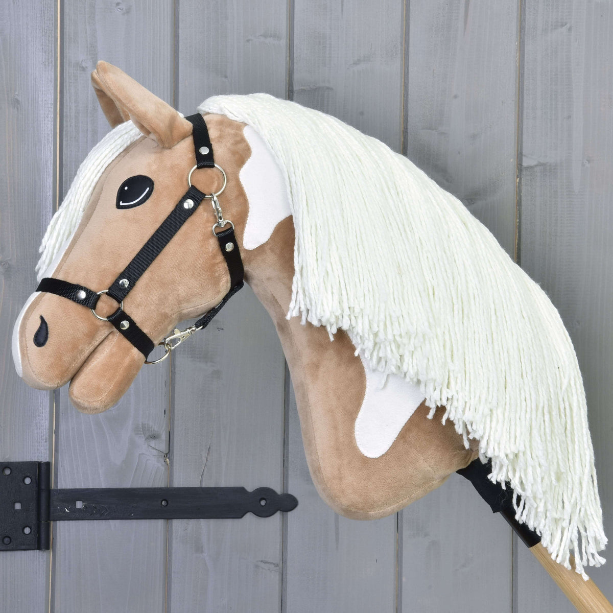 Hobby Horse Fury with a long cream yarn mane over the tan neck, a white neck patch and a black halter with silver rings