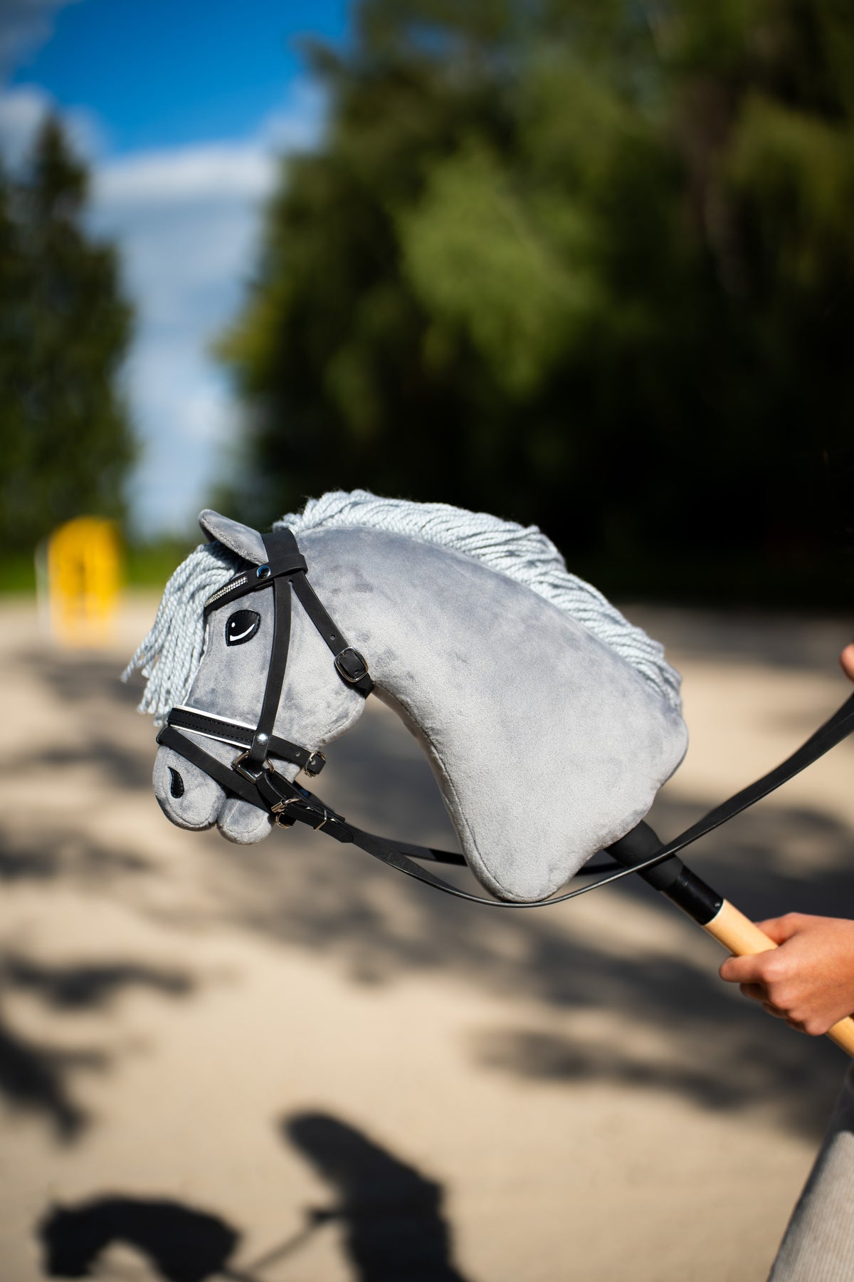 Hobby Horse Grace i svart träns med glittrande pannband, nosgrimma och tyglar, upphållen på en solig sandstig