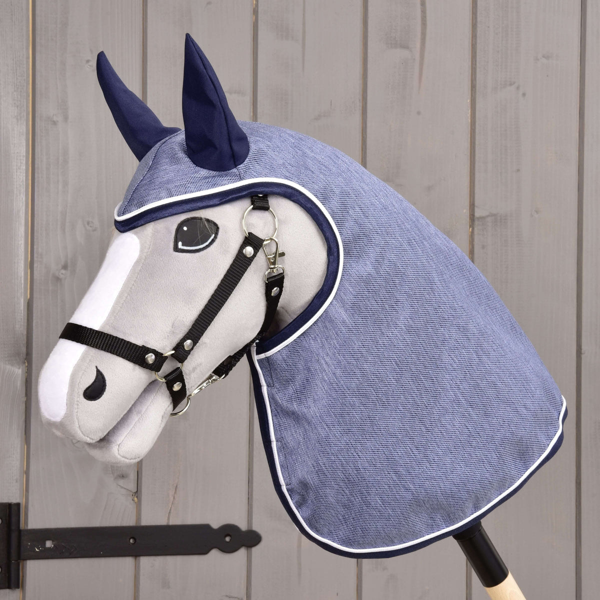 Light grey Hobby Horse in a black halter wearing the Raincoat Jeans, denim-blue fabric with navy ears and white piping