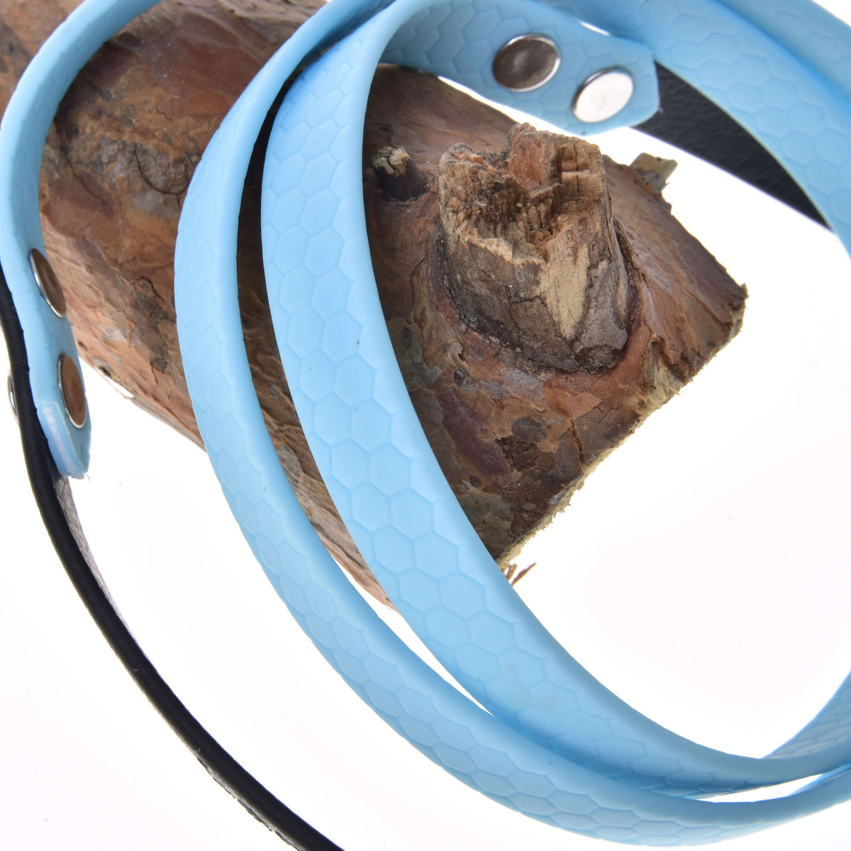 Close-up of light blue rubberized Hobby Horse reins with honeycomb texture and silver rivets, wrapped around a branch