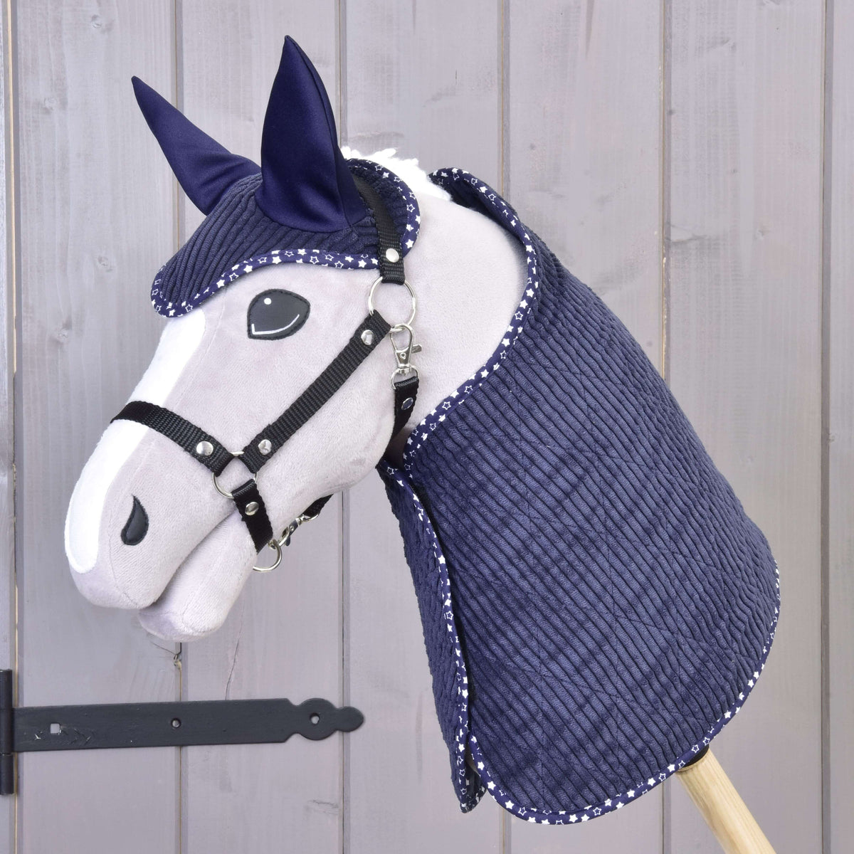 Grey Hobby Horse in a black halter wearing the navy corduroy blanket and ear bonnet with star-print edging
