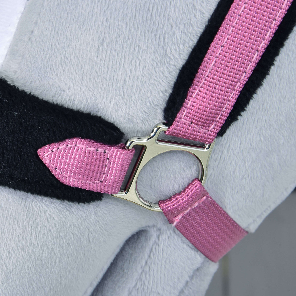 Close-up of the pink fur halter's silver ring fitting joining the pink webbing straps over black fur padding