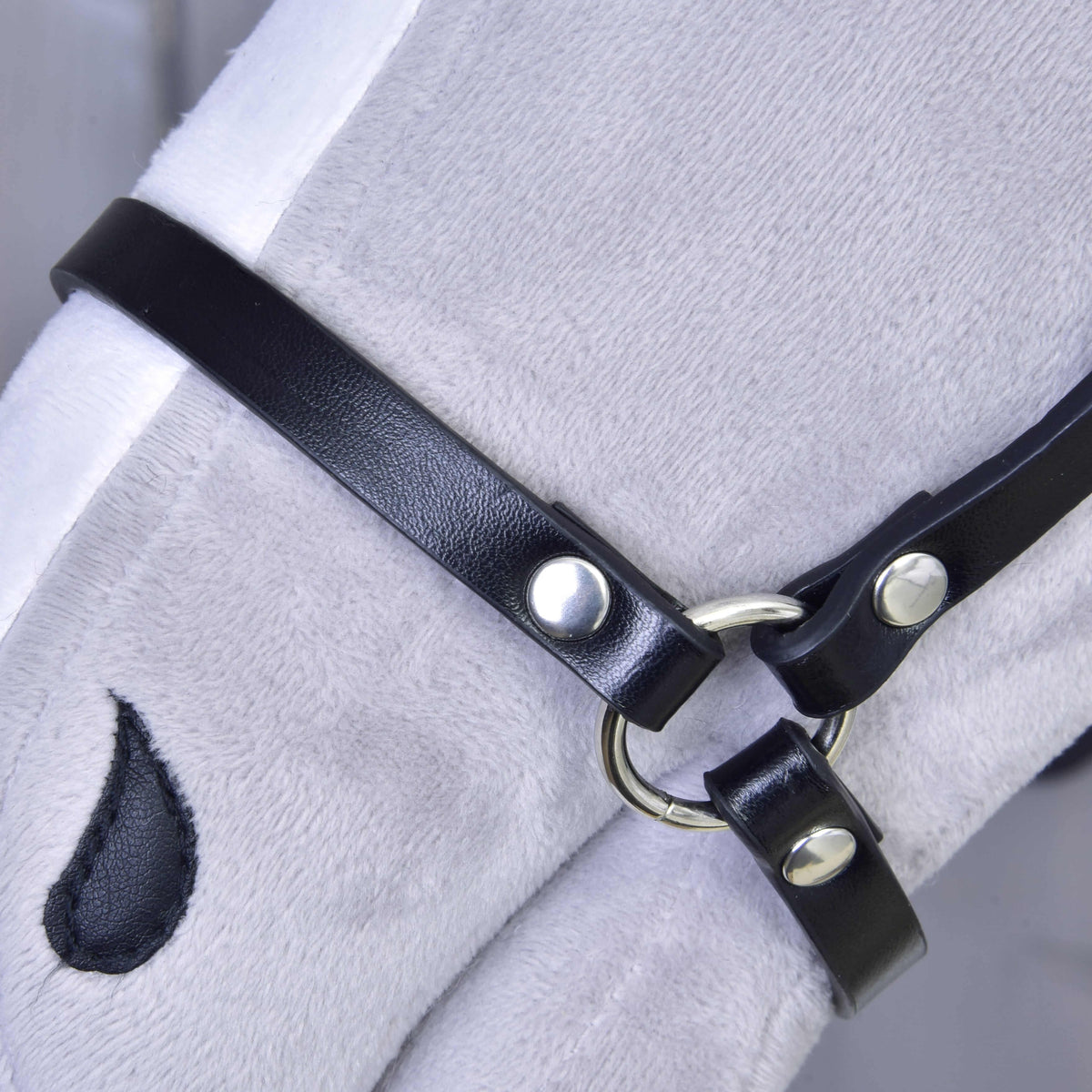 Close-up of the black leatherette halter noseband with a silver ring and rivets on a grey plush Hobby Horse