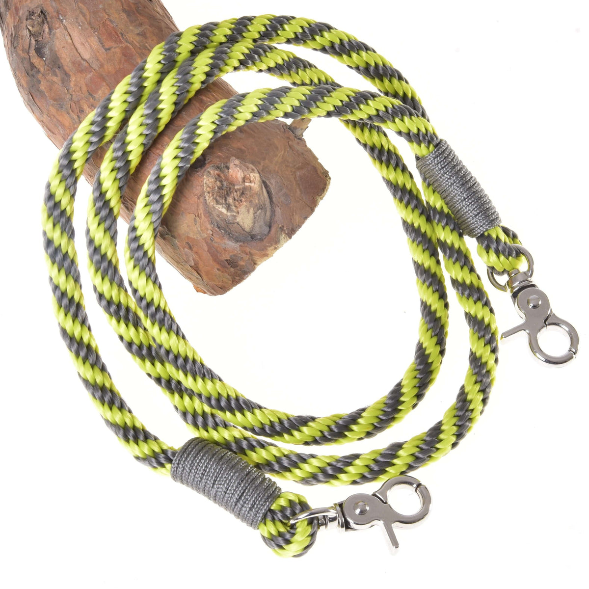 LarDen Hobby Horse Reins Lemon Stripe, lime and grey braided rope reins with silver snap hooks draped over a wooden branch
