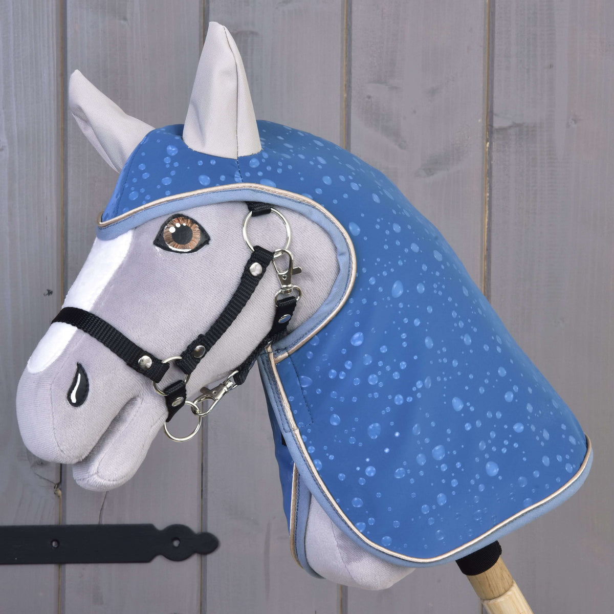 Grey plush Hobby Horse wearing the blue Raincoat Dolly with water droplet print and a black halter