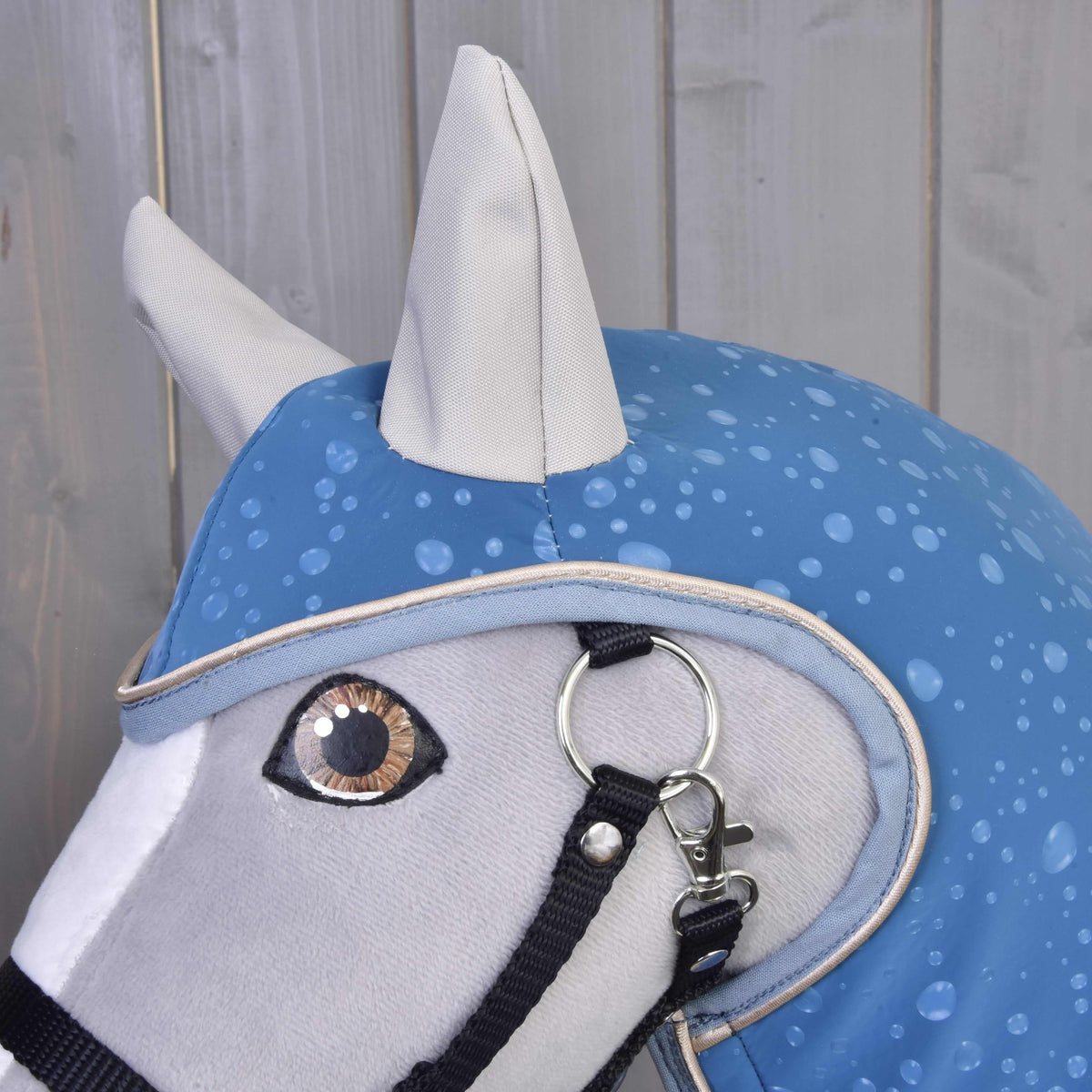 Close-up of the Raincoat Dolly hood with grey ear covers and droplet print over the eye of a grey Hobby Horse
