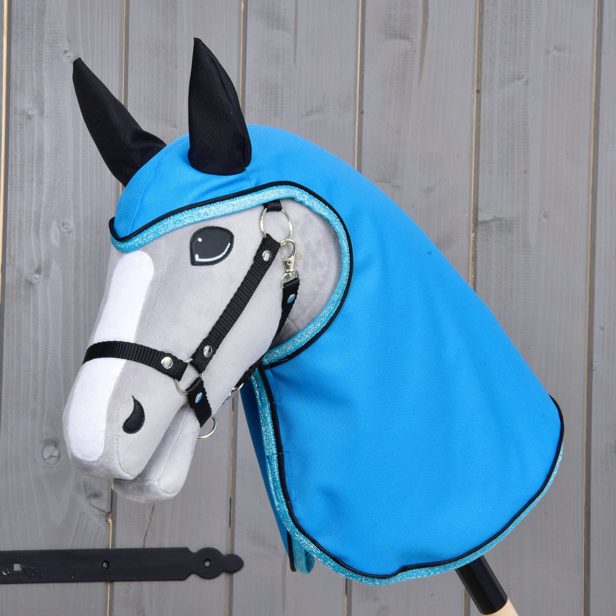 Light grey Hobby Horse with a black halter wearing the Raincoat Sky Blue, its hood with black ears and glittery blue trim