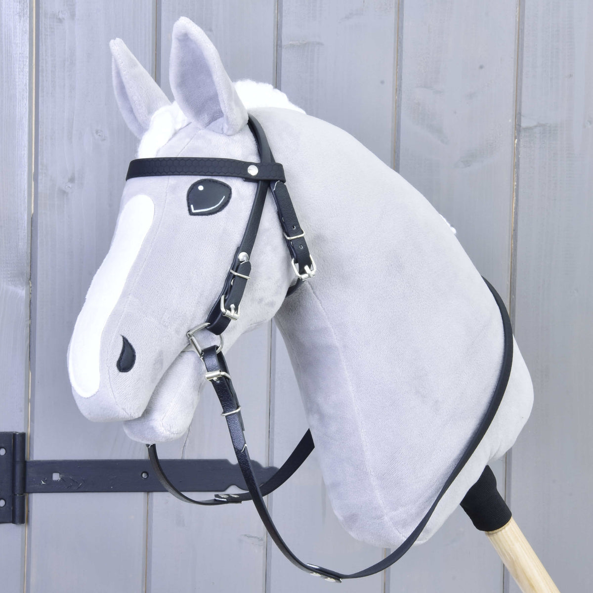 Grey Hobby Horse with a white blaze wearing the black bridle with browband, bit and reins but no noseband