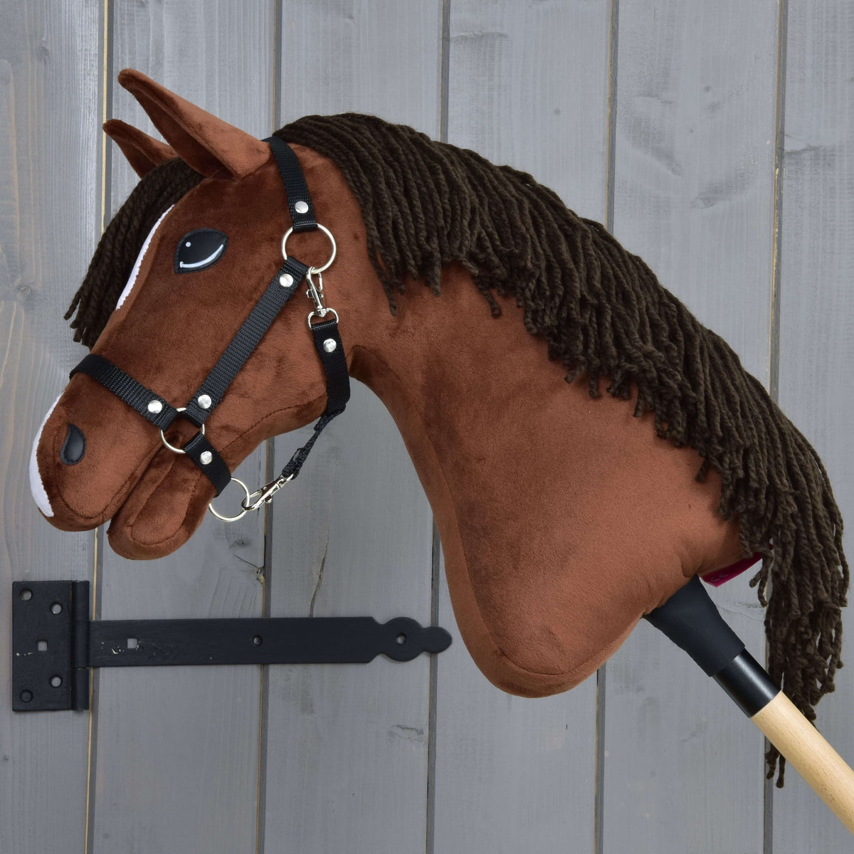 Hobby Horse Rocky i vänsterprofil med den långa mörkbruna manen av garn över den fuxfärgade halsen och svart grimma