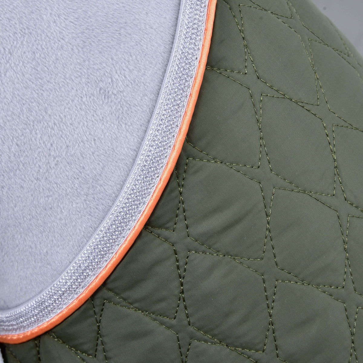 Close-up of the Set Moos blanket: olive green quilting, silver-grey binding and a thin orange piping