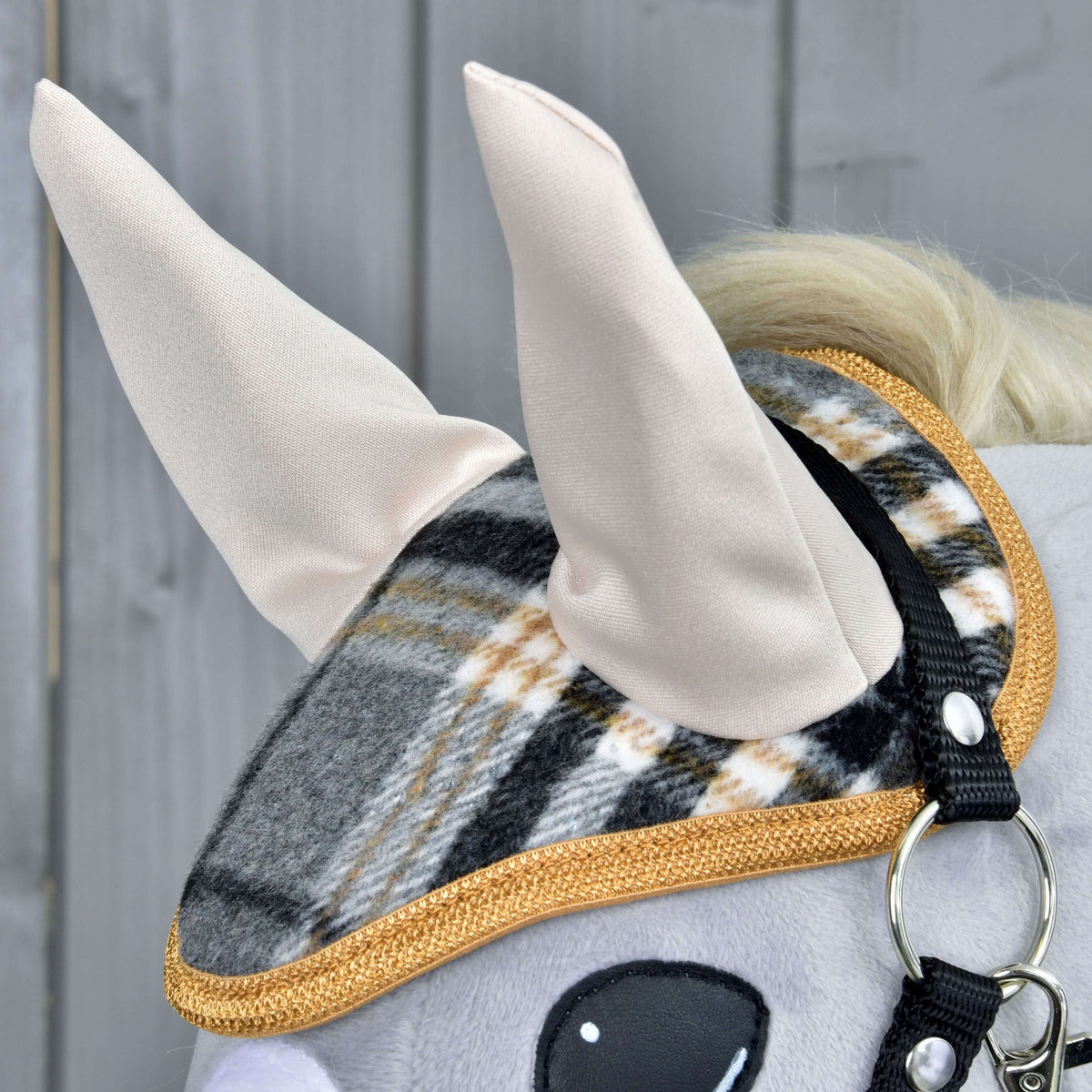 Close-up of the Set England Grey ear bonnet: cream ears, grey and black check and golden-brown braided trim