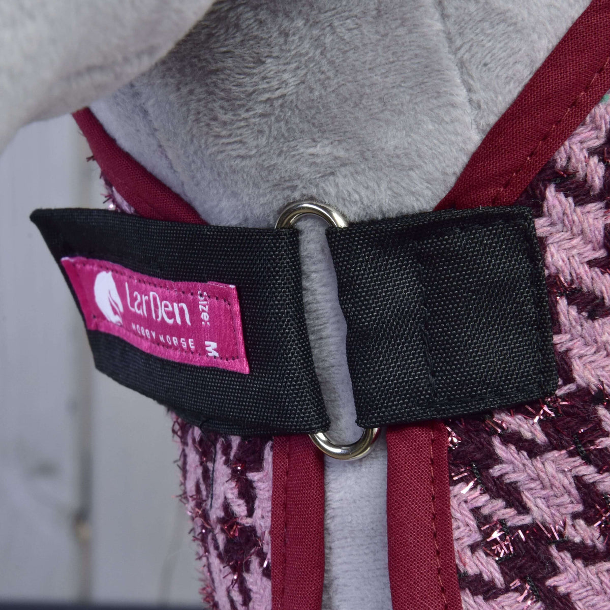 Chest closure of the Set Harmony Elsa blanket: black strap, metal ring, pink LarDen label and burgundy binding
