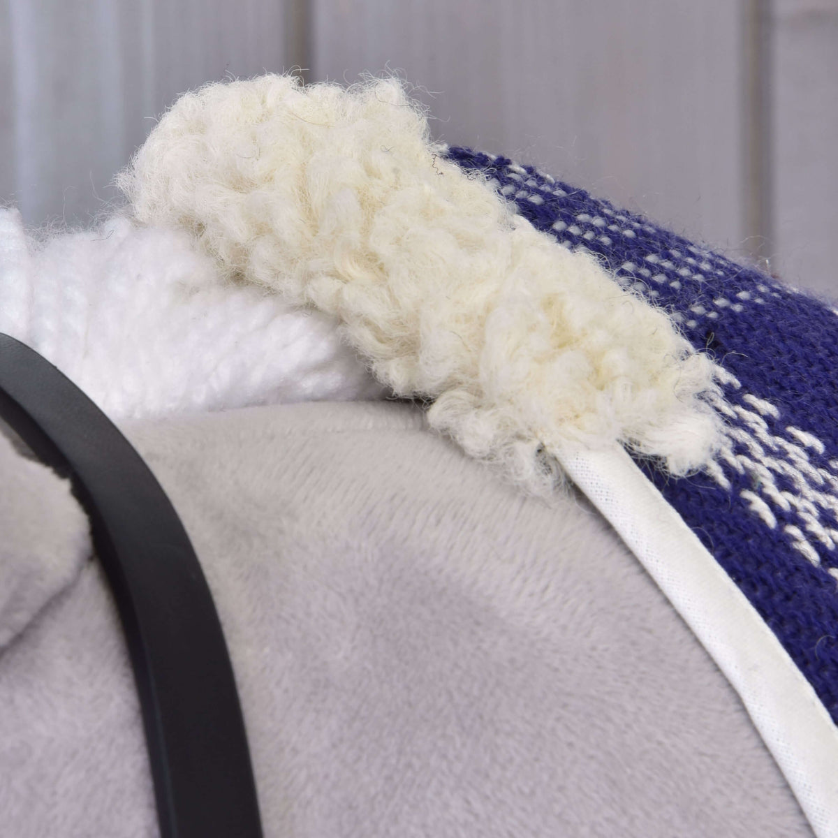 Close-up of the cream fleece collar and white piping on the dark blue and white plaid blanket of Set Harmony Victory