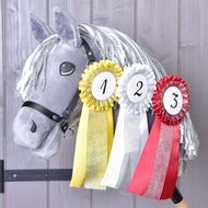 Grey plush Hobby Horse with a grey and white yarn mane wearing all three numbered rosettes on its neck